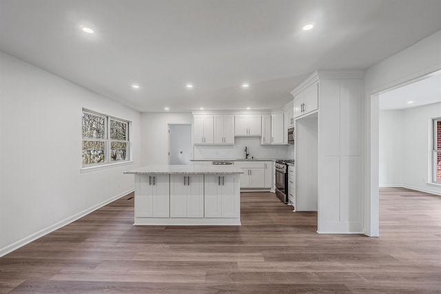 kitchen featuring white cabinetry, sink, a center island, stainless steel appliances, and light wood-type flooring