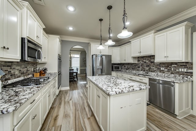 kitchen with white cabinetry, hanging light fixtures, stainless steel appliances, and a center island