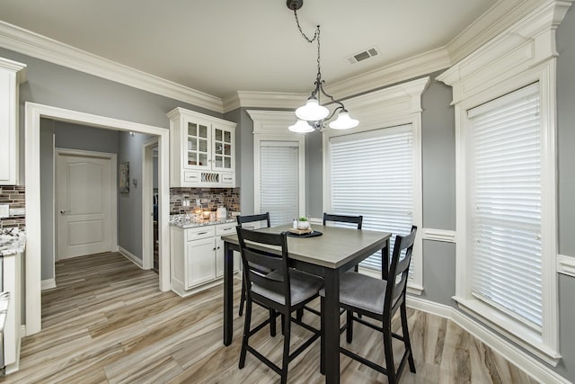 dining space featuring crown molding, light hardwood / wood-style floors, and a notable chandelier