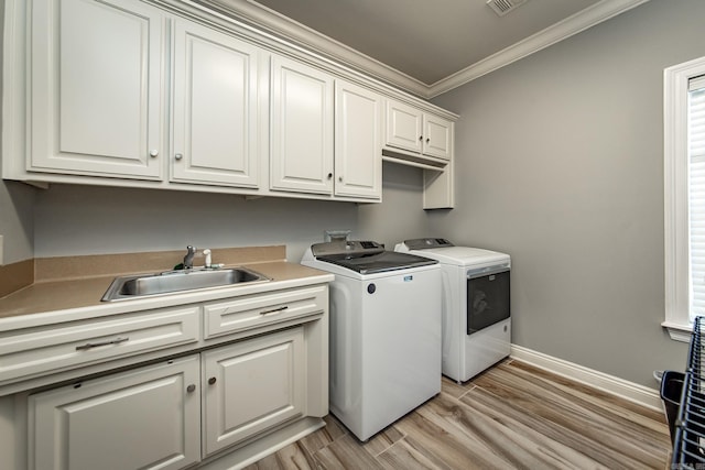 laundry room with sink, cabinets, ornamental molding, light hardwood / wood-style floors, and washing machine and dryer