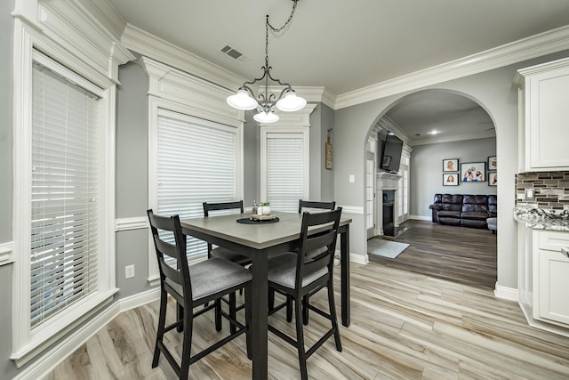 dining area featuring crown molding, a chandelier, and light hardwood / wood-style flooring