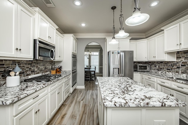 kitchen with hanging light fixtures, appliances with stainless steel finishes, a center island, and white cabinets