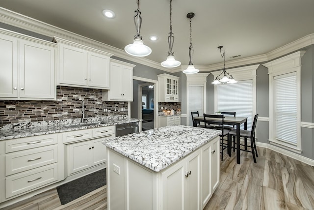 kitchen featuring sink, dishwasher, white cabinets, a kitchen island, and decorative light fixtures