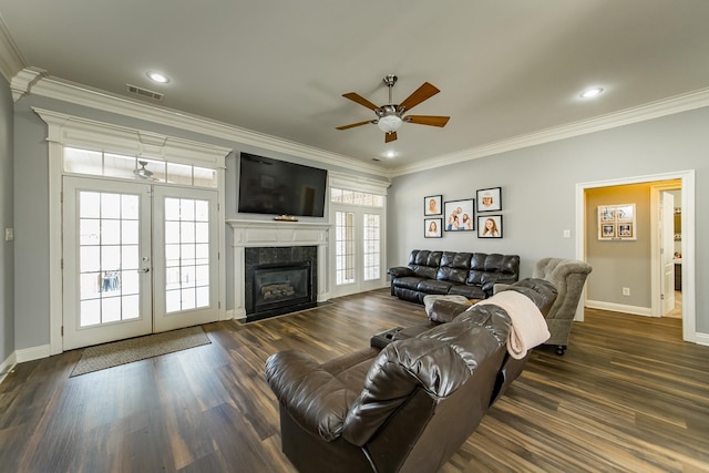 living room with a fireplace, dark hardwood / wood-style flooring, ceiling fan, crown molding, and french doors