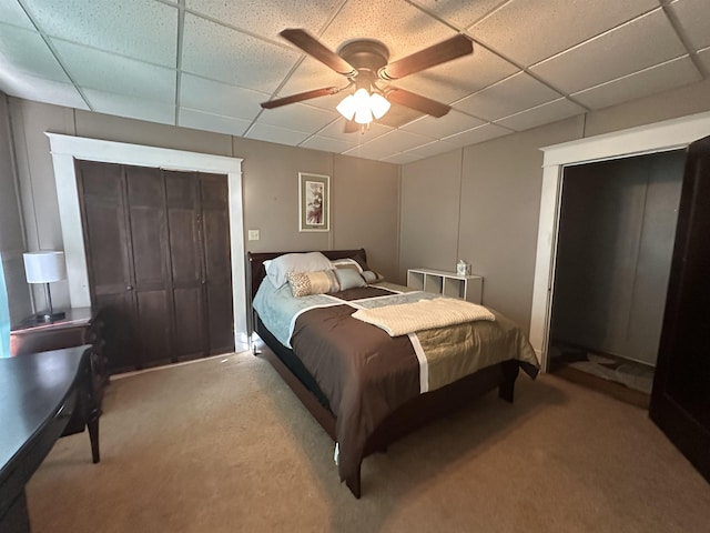 bedroom with ceiling fan, light colored carpet, and a drop ceiling