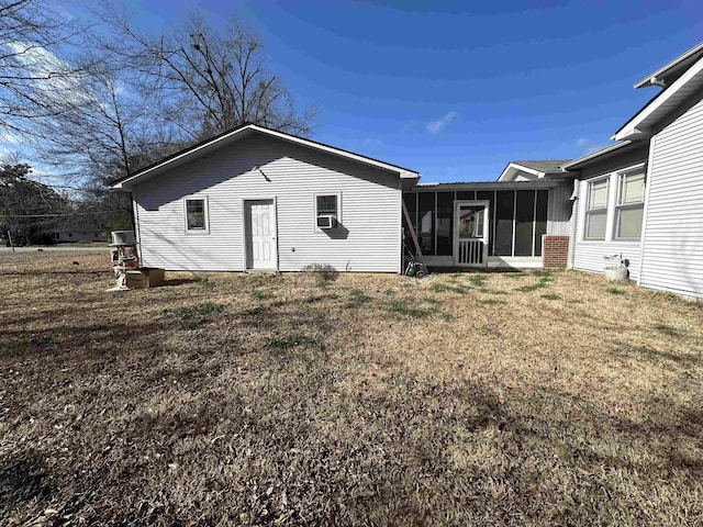 back of house featuring a sunroom and a lawn