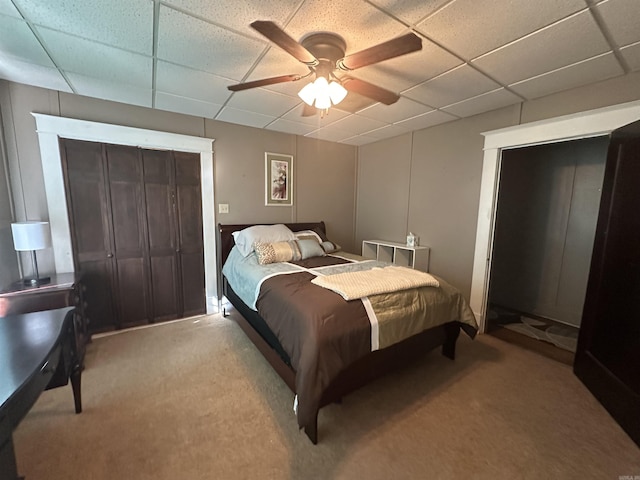 carpeted bedroom with ceiling fan and a drop ceiling