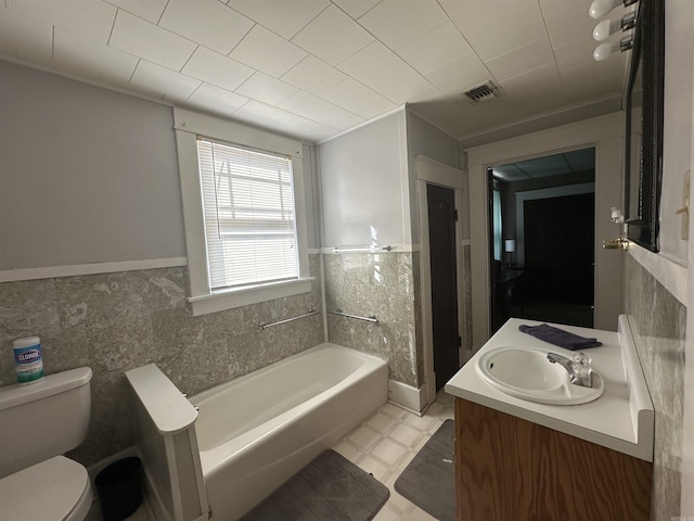 bathroom with vanity, a tub to relax in, tile walls, and toilet