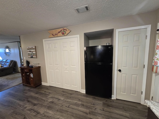 bedroom featuring black refrigerator, a textured ceiling, and dark hardwood / wood-style floors