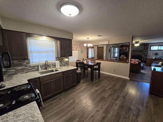 kitchen featuring dark wood-type flooring, dark brown cabinetry, sink, tasteful backsplash, and pendant lighting