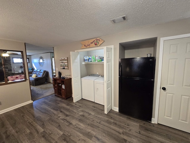 interior space with black fridge, dark hardwood / wood-style floors, washing machine and dryer, and a textured ceiling