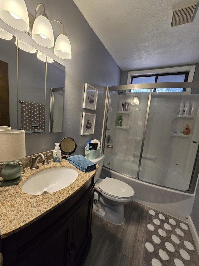 full bathroom featuring shower / bath combination with glass door, vanity, wood-type flooring, a textured ceiling, and toilet