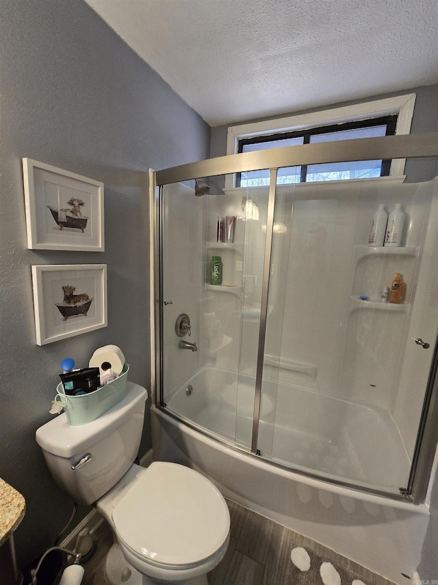 bathroom with hardwood / wood-style floors, combined bath / shower with glass door, toilet, and a textured ceiling