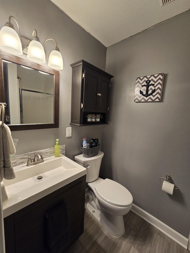 bathroom featuring vanity, toilet, wood-type flooring, and a textured ceiling