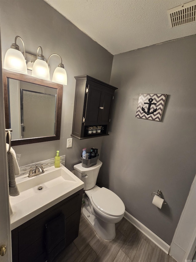 bathroom with vanity, wood-type flooring, a textured ceiling, and toilet