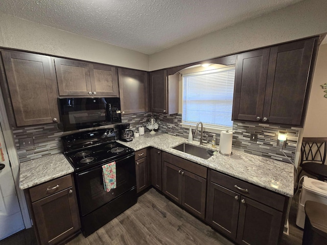 kitchen featuring dark brown cabinets, sink, light stone counters, and black appliances