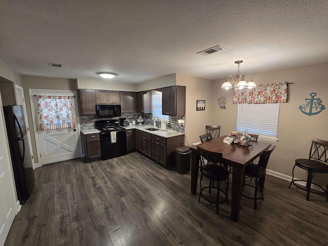 kitchen featuring pendant lighting, sink, dark hardwood / wood-style flooring, dark brown cabinetry, and black appliances