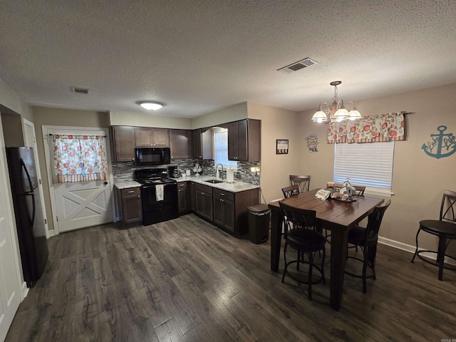 kitchen featuring pendant lighting, backsplash, dark brown cabinets, dark hardwood / wood-style floors, and black appliances