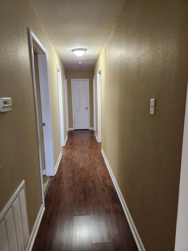 hallway with dark hardwood / wood-style flooring and a textured ceiling