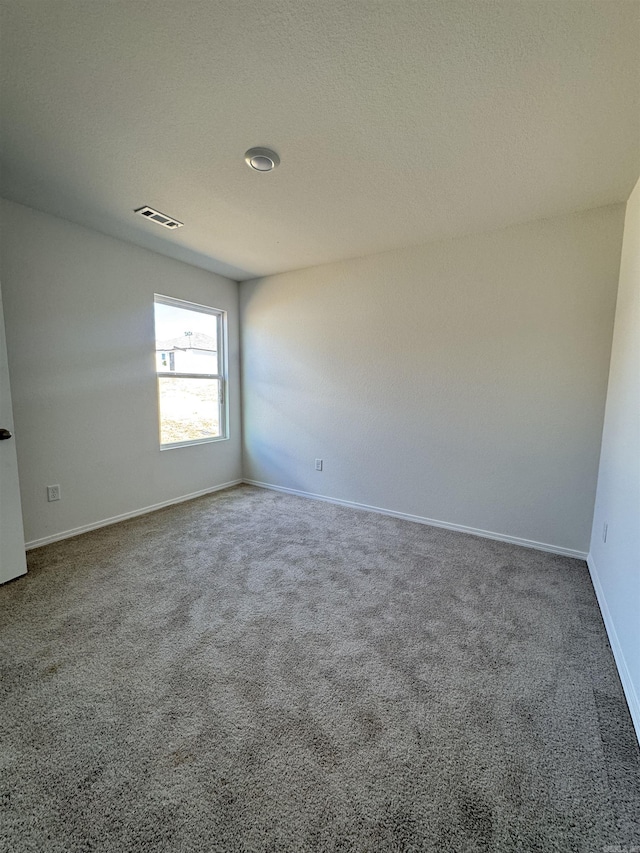 carpeted spare room featuring visible vents, a textured ceiling, and baseboards