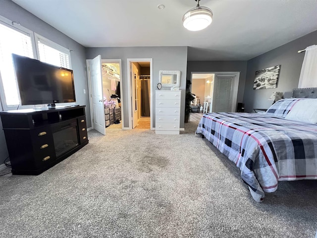 bedroom with light carpet, connected bathroom, a walk in closet, and a closet