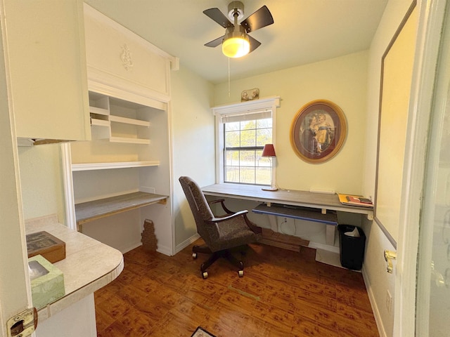 home office with dark hardwood / wood-style flooring, built in desk, and ceiling fan