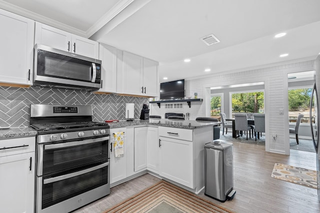 kitchen with white cabinetry, light hardwood / wood-style flooring, stone counters, and appliances with stainless steel finishes