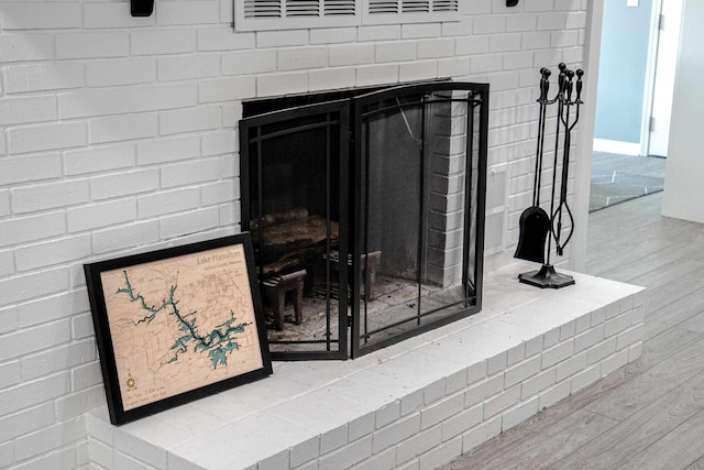 details featuring a brick fireplace and wood-type flooring