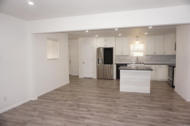 kitchen with sink, white cabinets, decorative backsplash, a center island, and stainless steel appliances