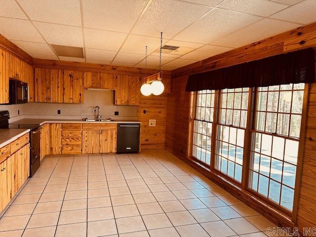 kitchen featuring a paneled ceiling, sink, light tile patterned floors, and black appliances