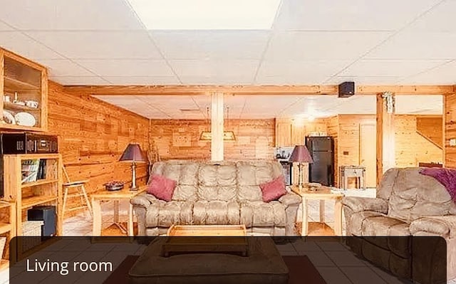 living room with tile patterned floors, wooden walls, and a drop ceiling