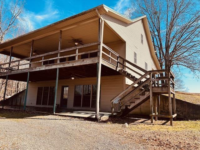 back of house featuring a wooden deck, ceiling fan, and a patio