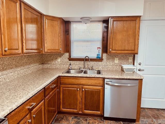 kitchen featuring tasteful backsplash, dishwasher, sink, and light stone counters