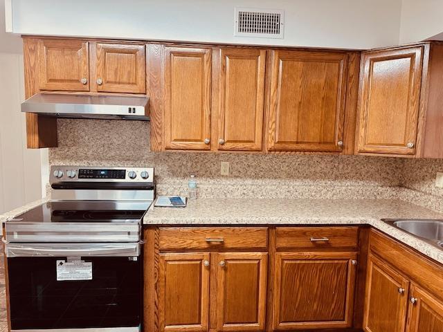 kitchen featuring electric stove, sink, and tasteful backsplash