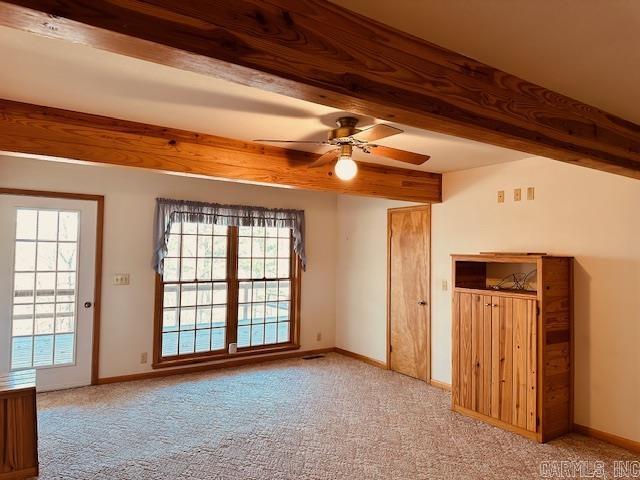 unfurnished room featuring beamed ceiling, light carpet, and ceiling fan