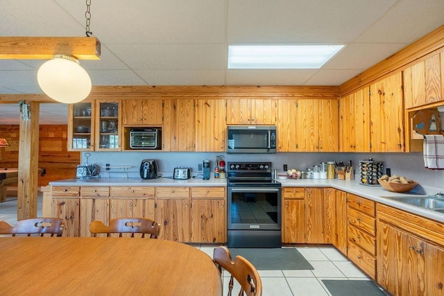 kitchen with pendant lighting, light tile patterned floors, sink, appliances with stainless steel finishes, and a drop ceiling