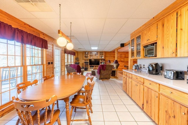 tiled dining space with a paneled ceiling and wood walls