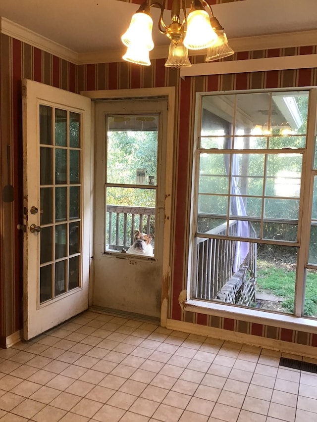 doorway to outside featuring tile patterned floors, ornamental molding, and a chandelier