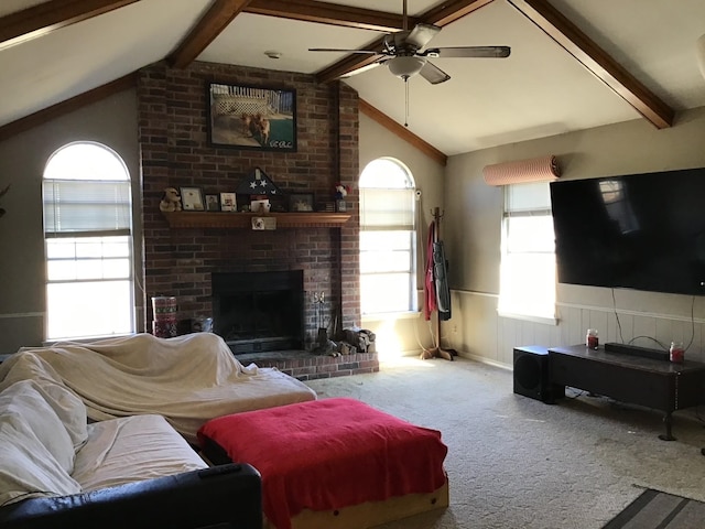 carpeted living room featuring a fireplace, lofted ceiling with beams, and ceiling fan