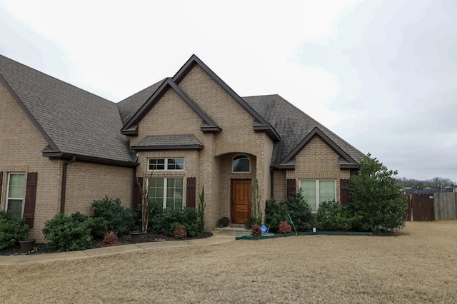 view of front facade featuring brick siding and roof with shingles