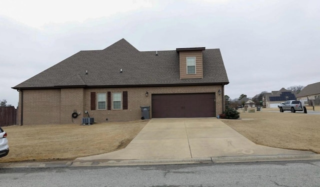 exterior space with a garage, central AC unit, concrete driveway, roof with shingles, and brick siding