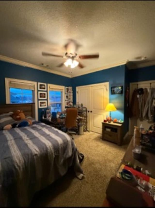 carpeted bedroom with ceiling fan, ornamental molding, and a textured ceiling