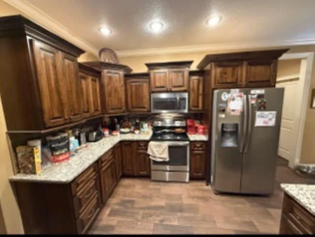 kitchen featuring appliances with stainless steel finishes, light stone counters, ornamental molding, dark brown cabinets, and recessed lighting