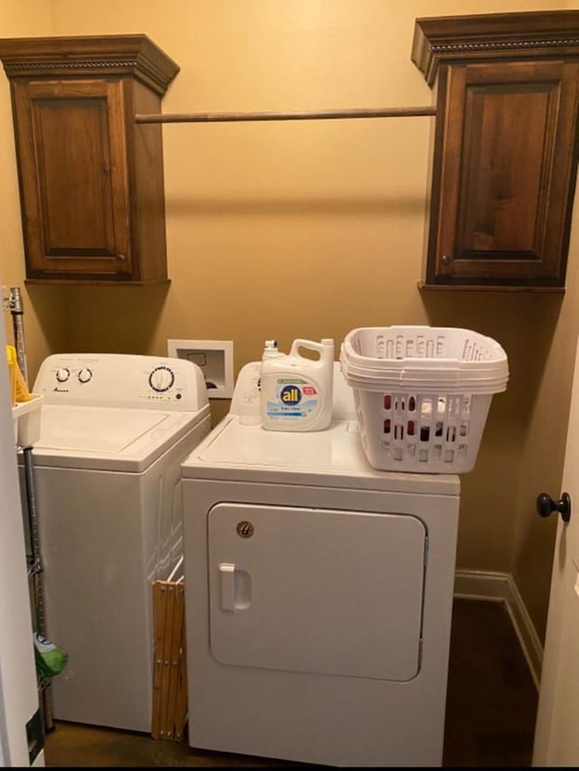 washroom featuring cabinet space, baseboards, and washer and clothes dryer