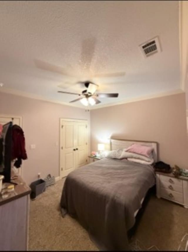 bedroom with ceiling fan, carpet floors, visible vents, and crown molding