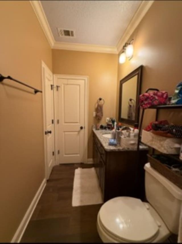 bathroom featuring toilet, visible vents, baseboards, vanity, and crown molding