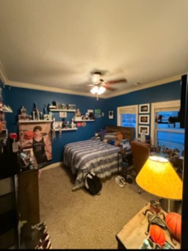 carpeted bedroom with ceiling fan and ornamental molding