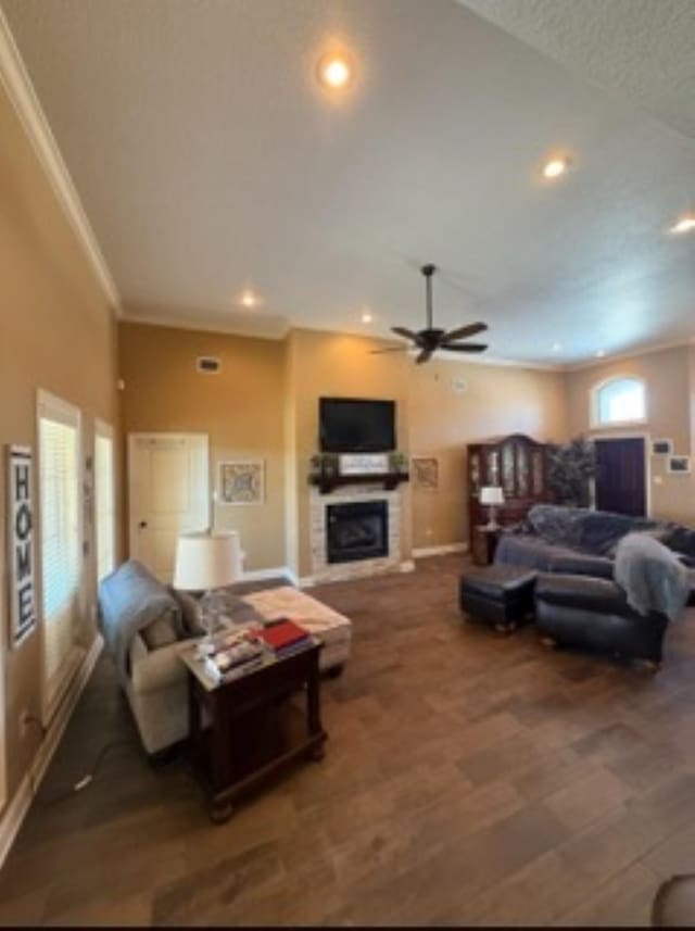 living room with recessed lighting, wood finished floors, baseboards, ornamental molding, and a glass covered fireplace