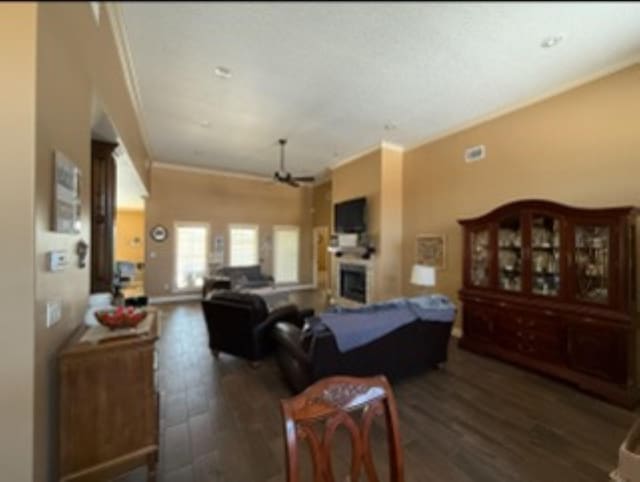 living room featuring ornamental molding, wood finished floors, a fireplace, and a ceiling fan