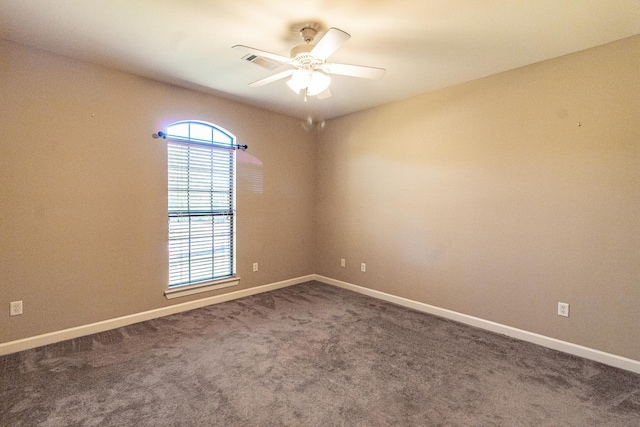 unfurnished room with ceiling fan and dark carpet